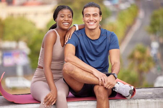 Ioga fitness e retrato de casal na cidade em pausa após treinamento ou treino de alongamento Amor casal interracial e homem e mulher sentados ao ar livre na esteira após o exercício de pilates para o bem-estar