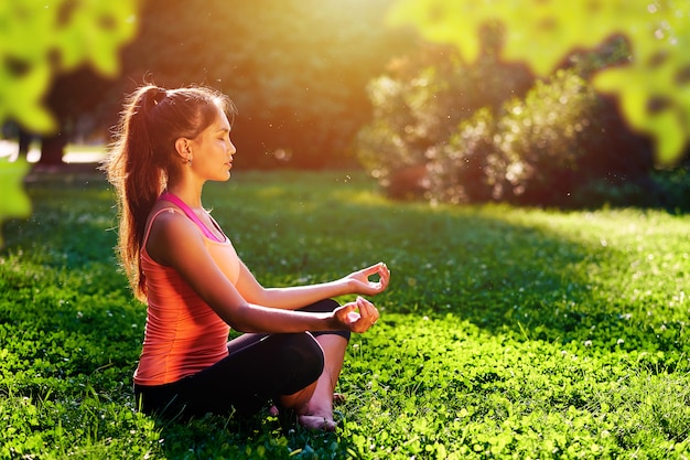 Ioga. Jovem mulher praticando ioga ou dançar ou esticar na natureza no parque. Conceito de estilo de vida de saúde