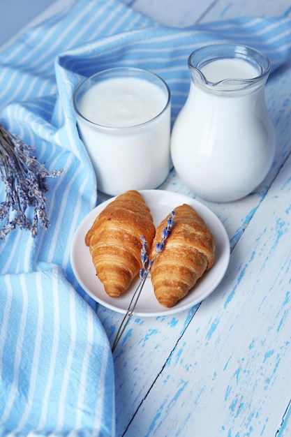 Iogurte caseiro em jarro e saborosos croissants no fundo da mesa de madeira