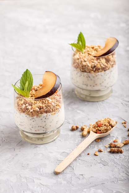 Iogurte com ameixa, sementes de chia e granola em uma colher de pau e madeira