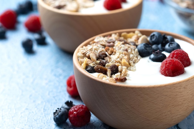 Iogurte com frutas e muesli no café da manhã na tigela sobre fundo azul