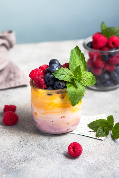 Iogurte com geléia de manga e frutas vermelhas com mirtilo, framboesa e folhas de hortelã no copo