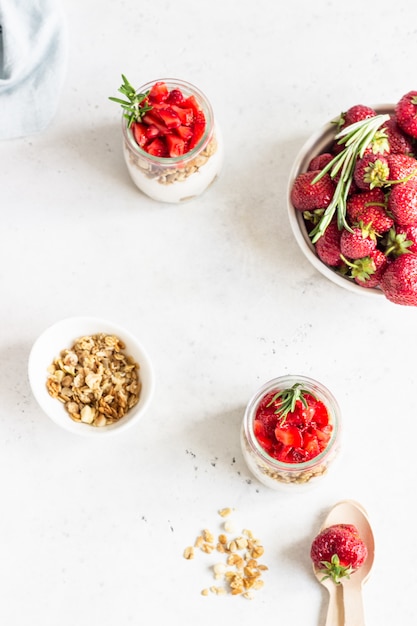 Iogurte de baga com iogurte grego, morangos frescos e granola em potes. parfait de café da manhã saudável em copo de vidro