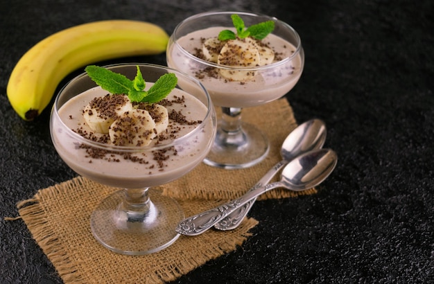 Iogurte de banana com canela e granola em copos.