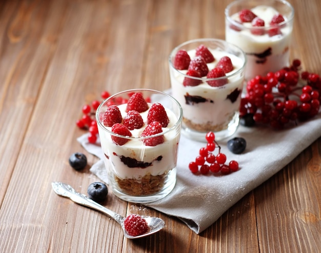 Iogurte de café da manhã saudável com frutas frescas e muesli servido em frasco de vidro com fundo de madeira
