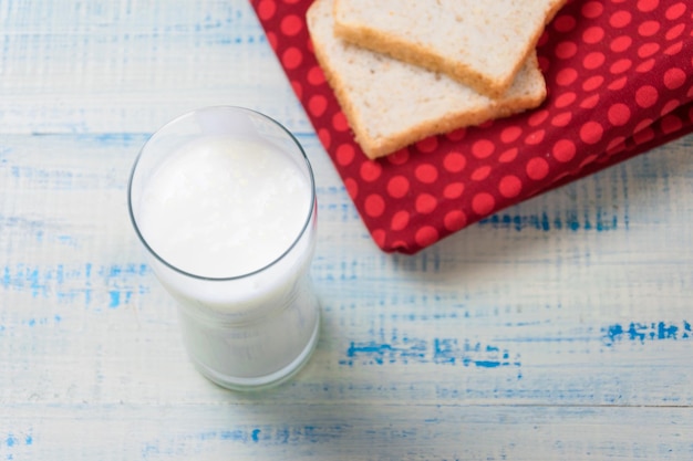 Iogurte de kefir em um copo em um fundo de fatias de pão branco em um fundo de madeira