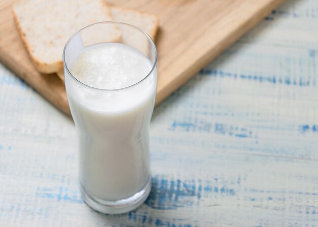 Iogurte de kefir em um copo em um fundo de fatias de pão branco em um fundo de madeira