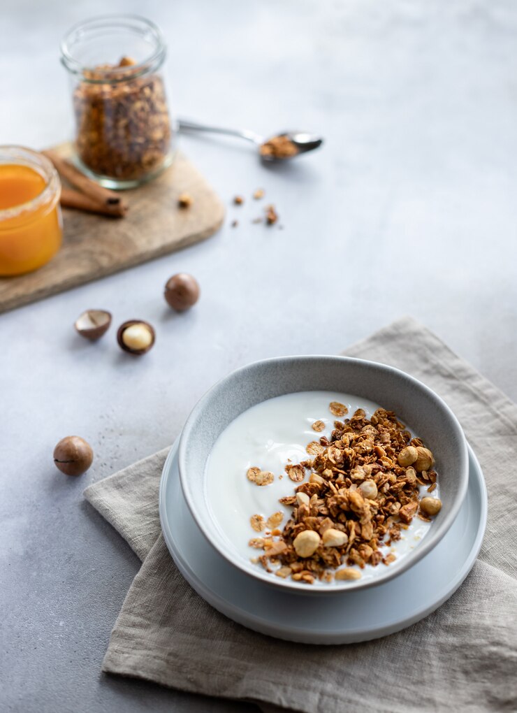 iogurte delicioso com granola, nozes e mel em uma tigela pequeno-almoço saudável, lanche espaço concreto cinza de fundo horizontal cópia