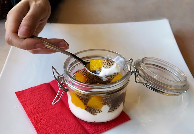 Iogurte do gosto da jovem mulher no restaurante.