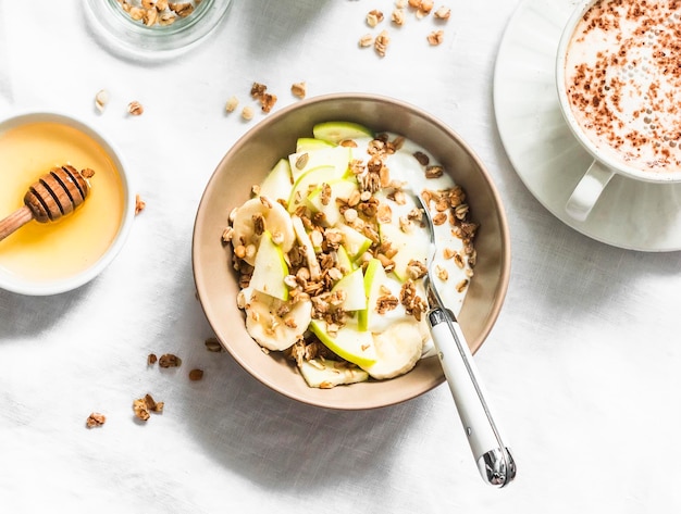 Iogurte grego com mel de maçã de banana granola em uma vista superior de fundo leve Delicioso café da manhã