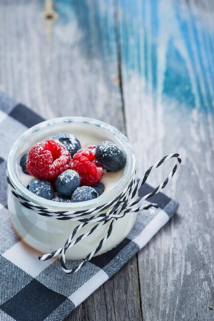 Iogurte natural fresco e saudável com frutas na mesa de madeira