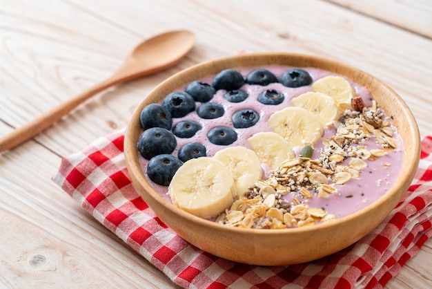 Iogurte ou tigela de smoothie de iogurte com baga azul, banana e granola - estilo de comida saudável