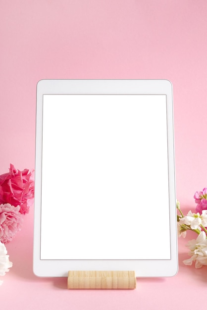 Ipad pro tablet com tela branca na cor rosa fundo flores escritório projeto mulher fundo