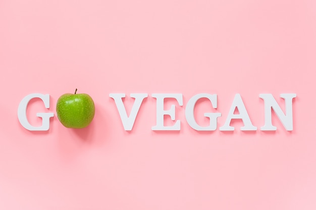 Ir o conceito de dieta saudável vegan. maçã verde natural fresca na palavra go vegan de letras brancas