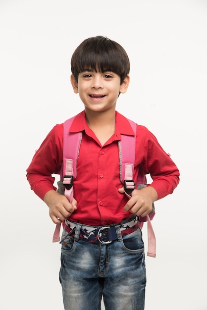 Ir para a escola - Menino indiano ou asiático bonitinho de camisa vermelha e jeans jeans com bolsa escolar, isolado sobre um fundo branco