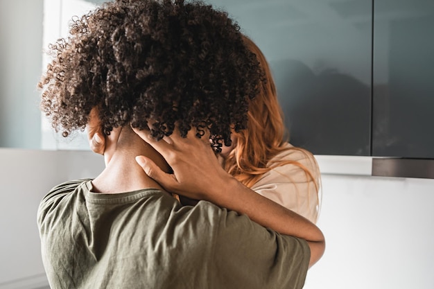 Foto irassische lesbische frauen, die einen leidenschaftlichen kuss in der rückansicht der küche haben