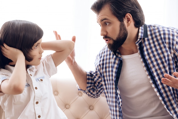 Irate pai repreende o filho adolescente que conecta as orelhas.