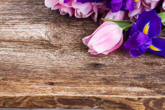 Iris azules y tulipanes pik sobre fondo envejecido de madera con espacio de copia