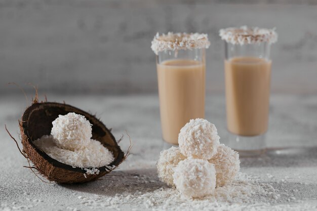 Irische sahne oder kaffeelikör mit hausgemachten gesunden kokosnussbällchen und kokosflocken auf heller oberfläche