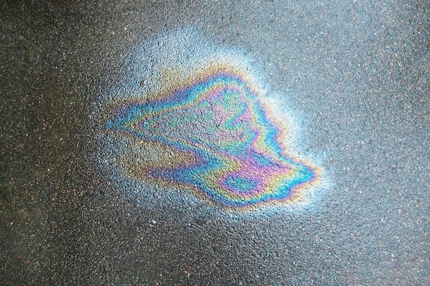 Irisierender Benzinfleck Benzin auf dem Asphalt eine große verschmutzte Wasserpfütze Ein regenbogenfarbener Benzinklecks