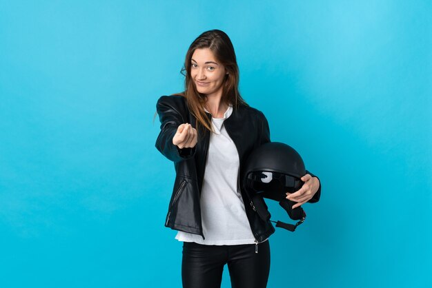 Irlanda joven mujer sosteniendo un casco de motocicleta aislado sobre fondo azul haciendo gesto de dinero