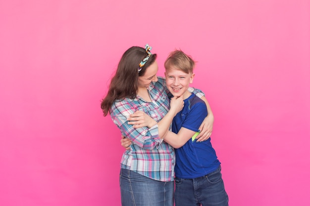 Irmã do retrato de família e irmão adolescente na parede rosa