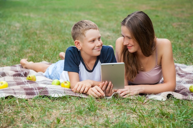 Irmã e irmão mais novos deitados e trabalhando com tablet