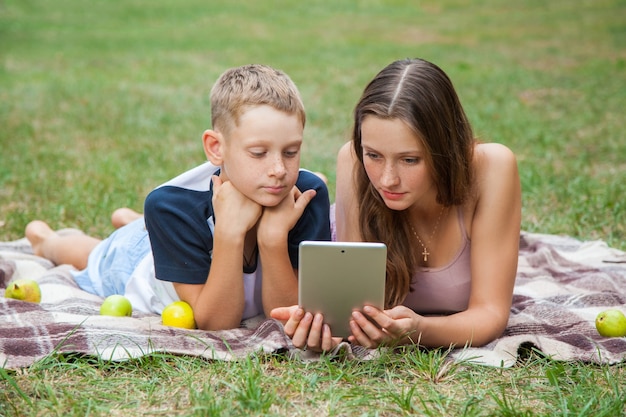 Irmã e irmão mais novos deitados e trabalhando com tablet