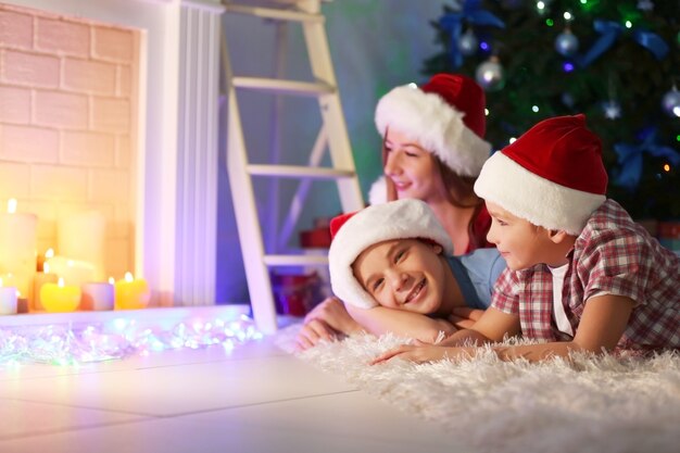 Irmã e irmãos felizes com presentes no chão em uma sala decorada de Natal