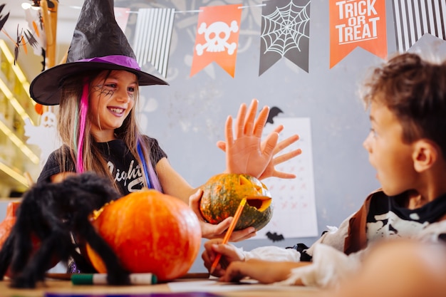 Irmão assustador. irmã engraçada e sorridente usando fantasia de halloween assustando irmão com biscoito de mão