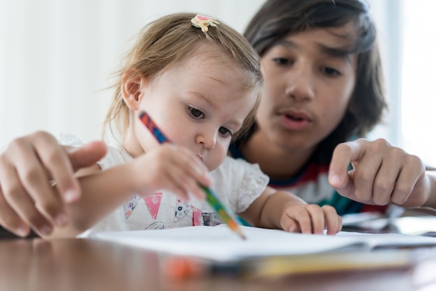 Irmão brincando e desenhando com sua irmãzinha