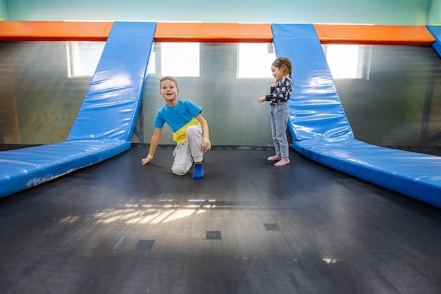 Irmão com irmã brincando no playground do centro de jogos indoor pulando na cama elástica