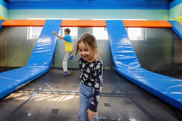 Foto irmão com irmã brincando no playground do centro de jogos indoor pulando na cama elástica