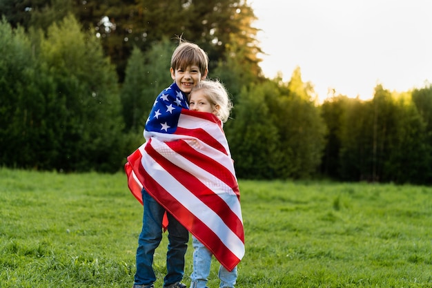 Irmão e irmã com a bandeira americana se abraçam, crianças felizes no dia da independência dos estados unidos.