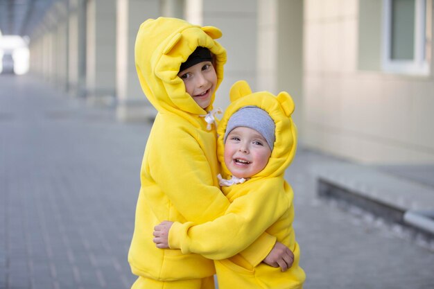 Irmão e irmã, crianças engraçadas, rapaz e rapariga de terno amarelo, abraçam-se.