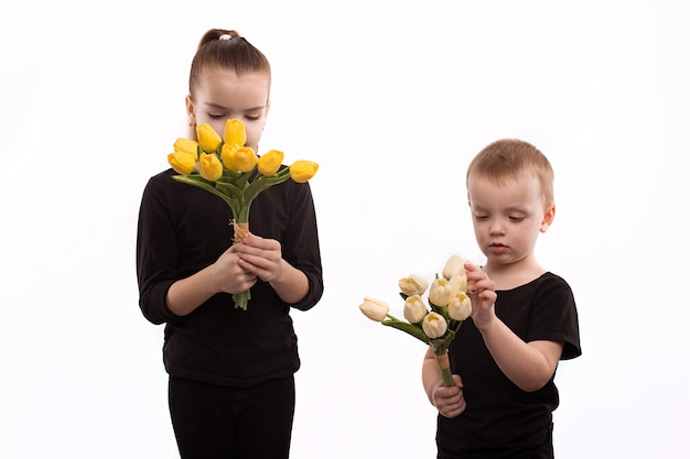 Irmão e irmã em blusas pretas segurando as tulipas nas mãos