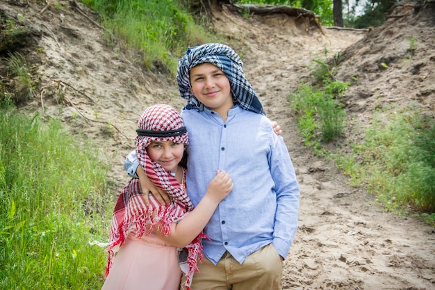 Irmão e irmã em traje hindu e árabe na natureza no verão