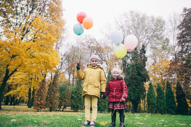 Irmão e irmã em um parque de outono com balões
