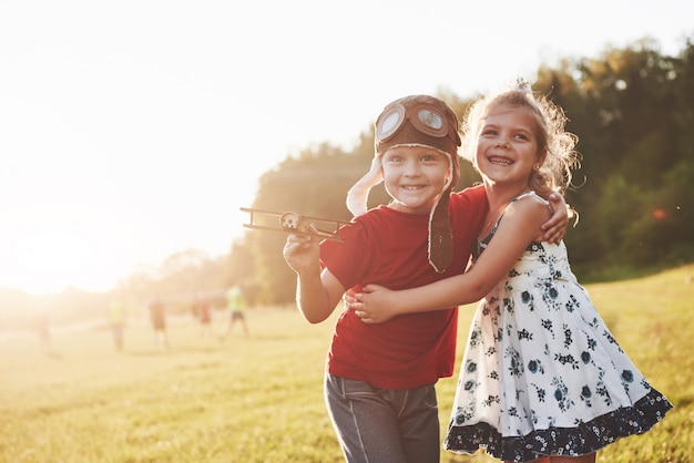 Foto irmão e irmã estão brincando juntos. duas crianças brincando com um avião de madeira ao ar livre