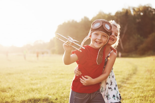 Irmão e irmã estão brincando juntos. Duas crianças brincando com um avião de madeira ao ar livre