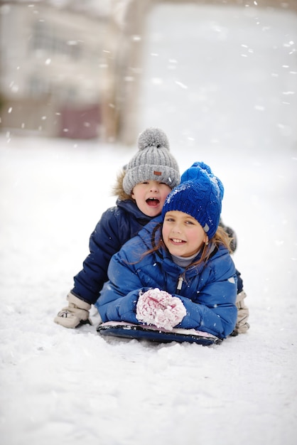 Irmão e irmã felizes brincando na neve