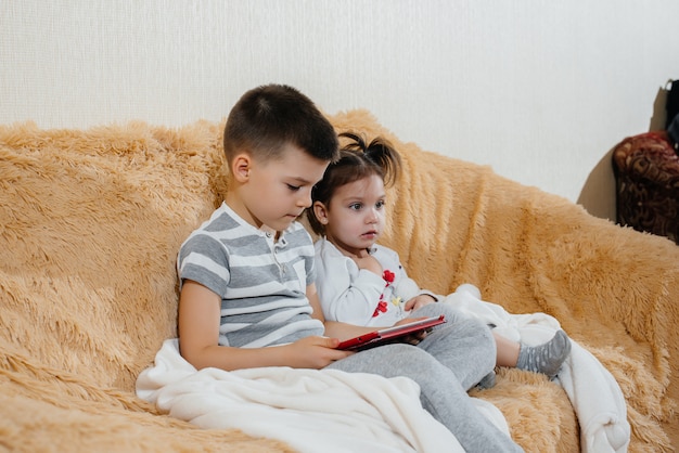 Irmão e irmã jogam no sofá no tablet