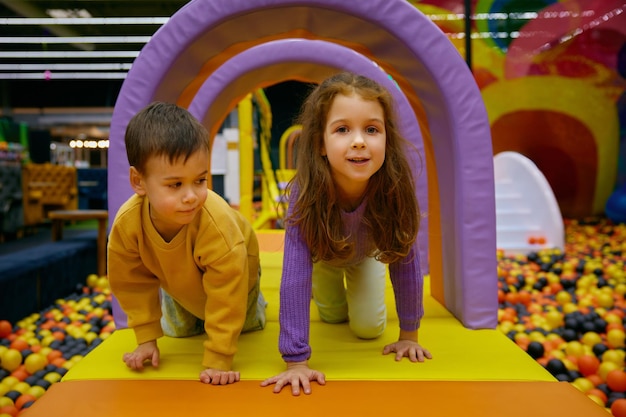 Irmão e irmã pequenos crianças positivas brincando no parque coberto