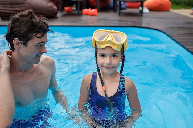 Irmão mais velho treinando irmão mais novo para nadar na piscina ao ar livre no verão estilo de vida saudável