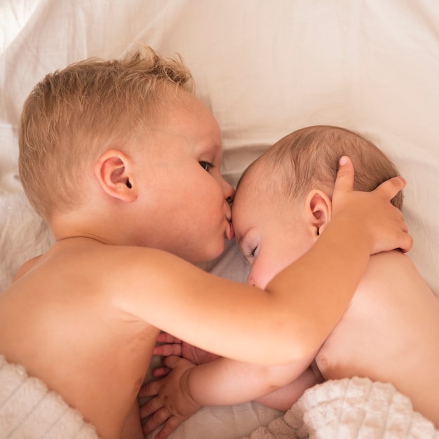 Foto irmão que beija o bebê recém-nascido na testa