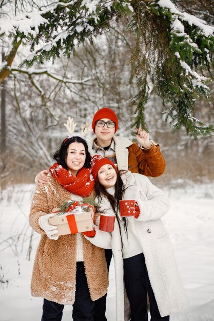 Irmãos adolescentes e sua mãe em winter park com uma caixa de presente