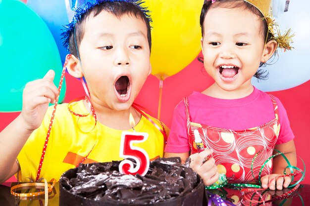 Irmãos bonitos com bolo de aniversário em casa.