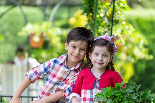 Irmãos com roupas combinando e sorrindo para a câmera rodeada pela natureza