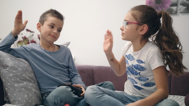 Irmãos dão cinco mãos aos videogames Crianças se divertem juntas em casa