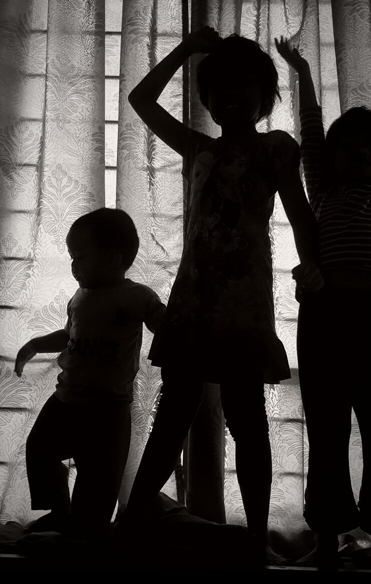 Foto irmãos de pé contra a cortina em casa